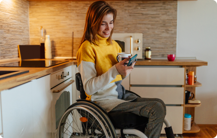 Woman using a smartphone while seated in a wheelchair, accessing digital financial services.